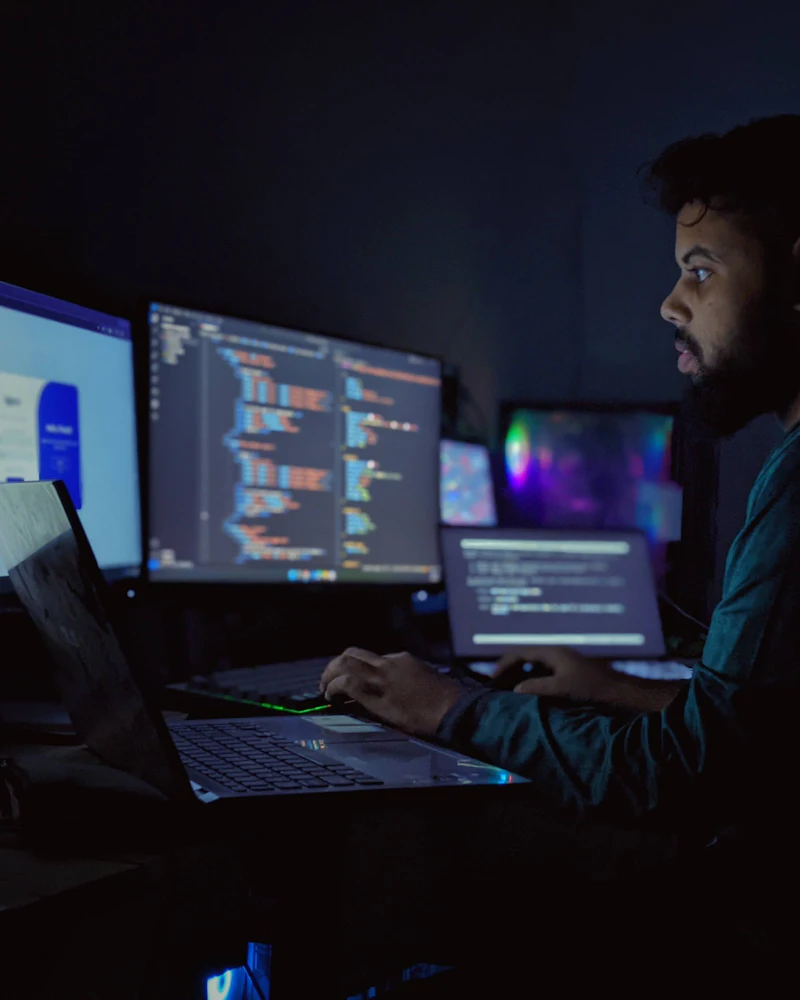 Engineer working on code across several monitors